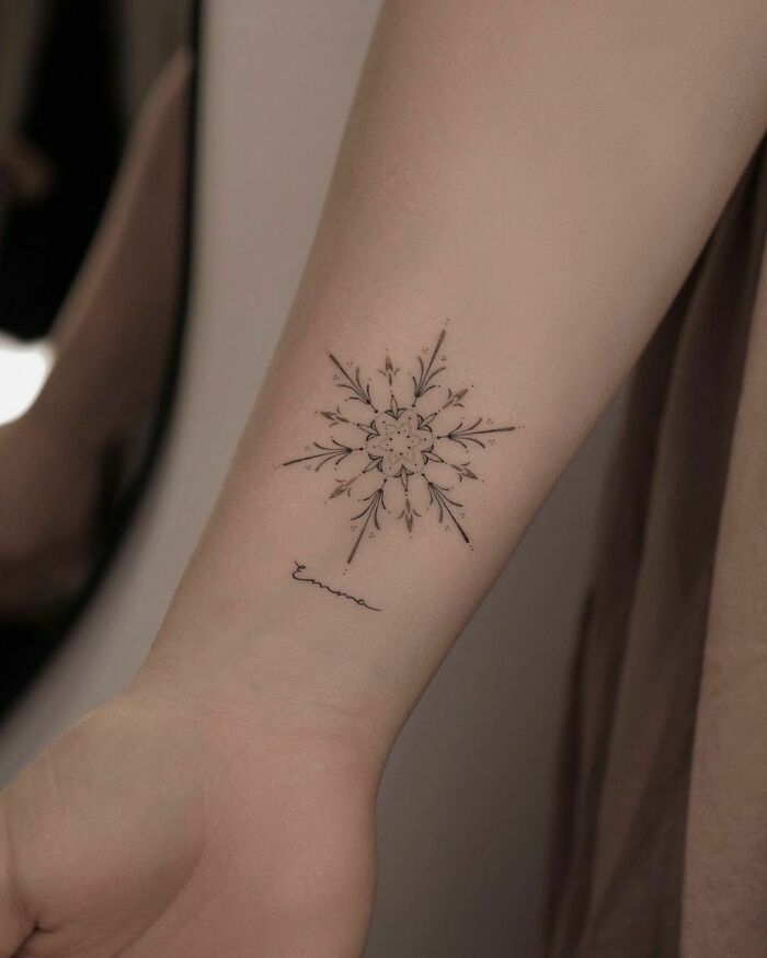 Delicate wrist tattoo design featuring a star-like floral pattern with intricate details.