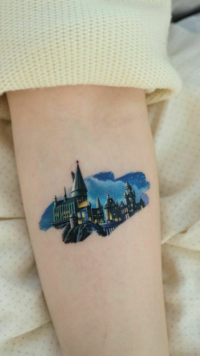 Color tattoo by Saegeem depicting a detailed, museum-worthy night scene of a castle on a forearm.