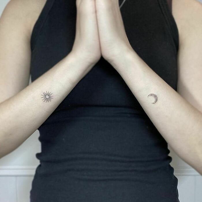Minimalist wrist tattoos featuring sun and crescent moon designs on both arms.