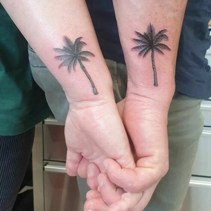 Matching palm tree wrist tattoos on two arms, showcasing stylish wrist tattoo design.