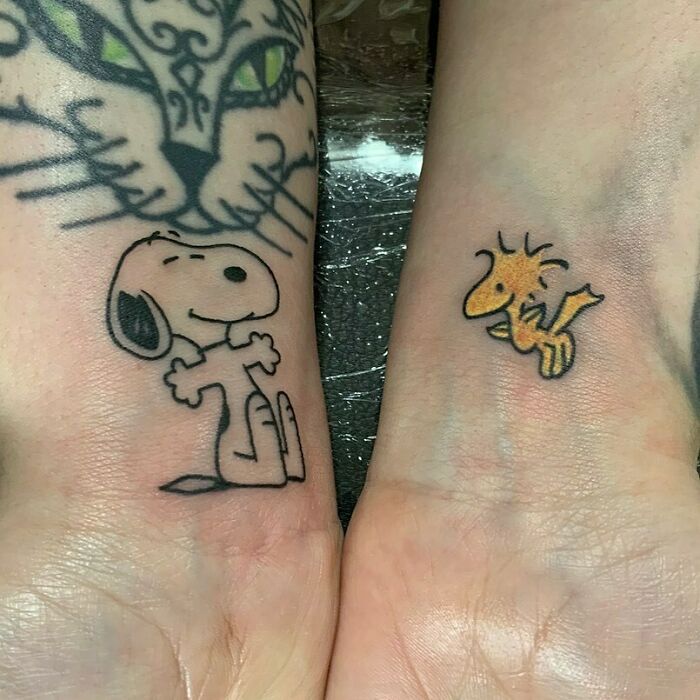 Cartoon wrist tattoo designs featuring nostalgic characters with a backdrop of a cat tattoo.