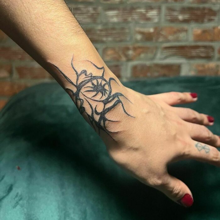 Tribal wrist tattoo with abstract design on a person's wrist, featuring intricate black line work.