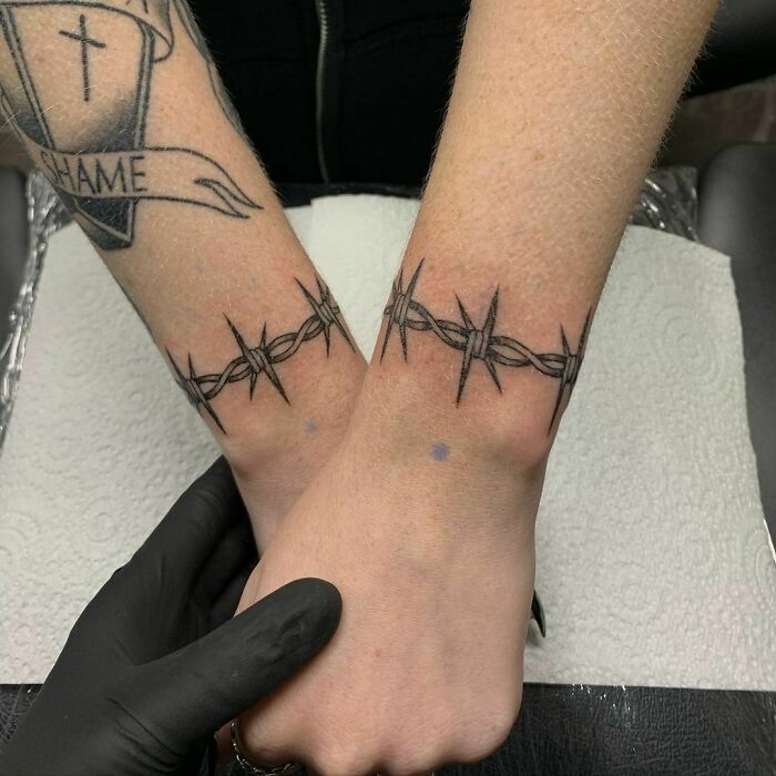 Close-up of barbed wire wrist tattoo design on both wrists.