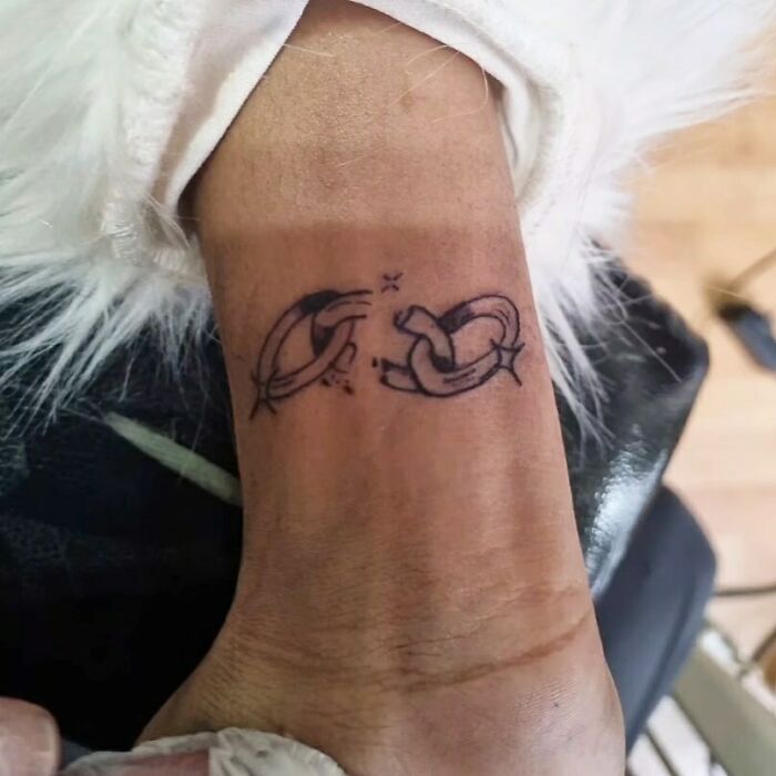 Wrist tattoo of two hands linking together in a minimalist design.