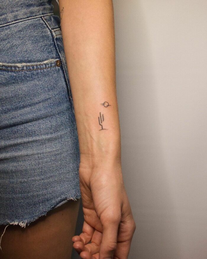 Minimal wrist tattoo of a cactus and sun, showcasing a simple and elegant wrist design.