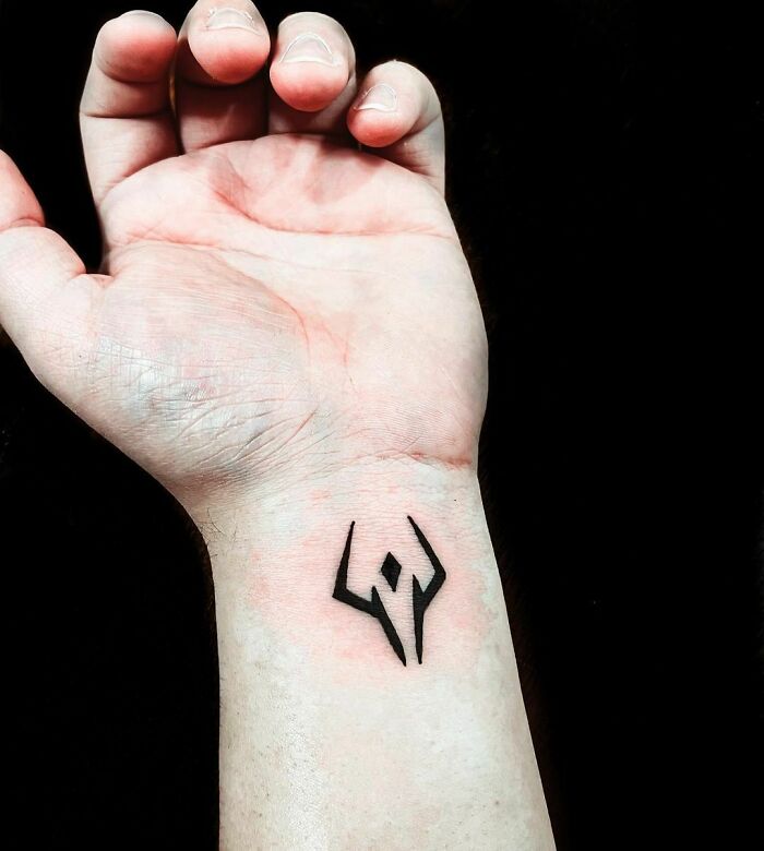 Geometric wrist tattoo design in black ink on an inner wrist.