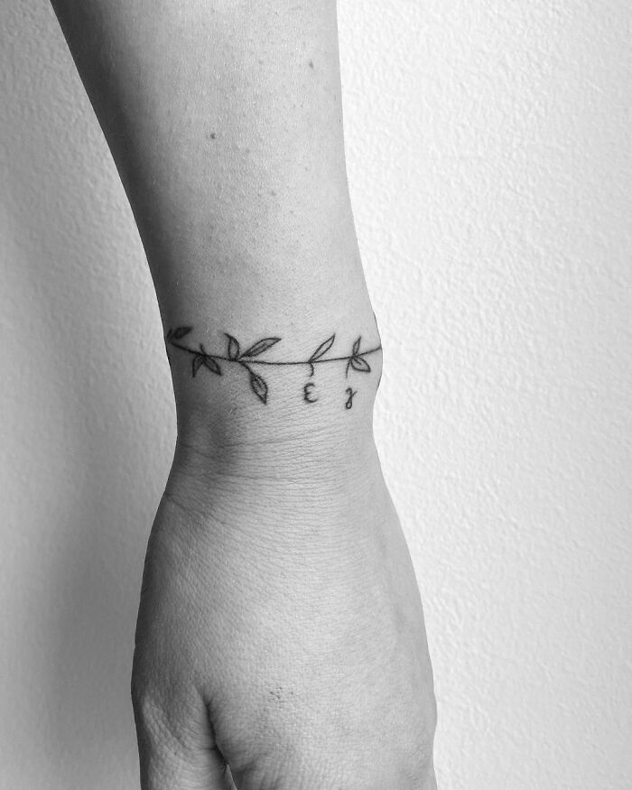Minimalist wrist tattoo with a delicate leaf design, showcasing timeless accessory style.