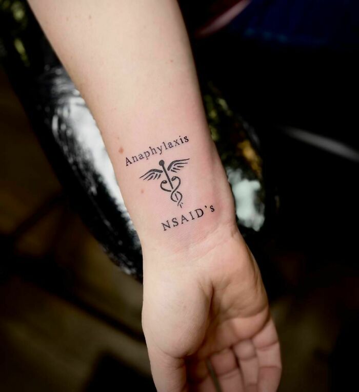 Wrist tattoo with medical warning for anaphylaxis and NSAIDs, featuring a caduceus symbol.