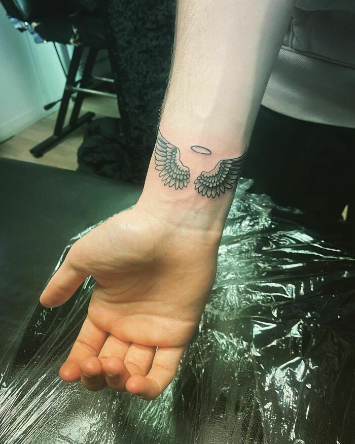 Wrist tattoo featuring angel wings and a halo design, making a statement on skin.