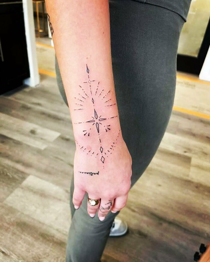 Geometric wrist tattoo design with starburst pattern.