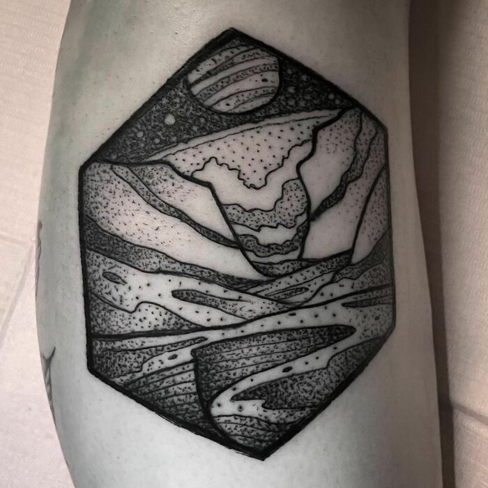 Hexagonal geometric tattoo with abstract mountain and planet design in black ink.