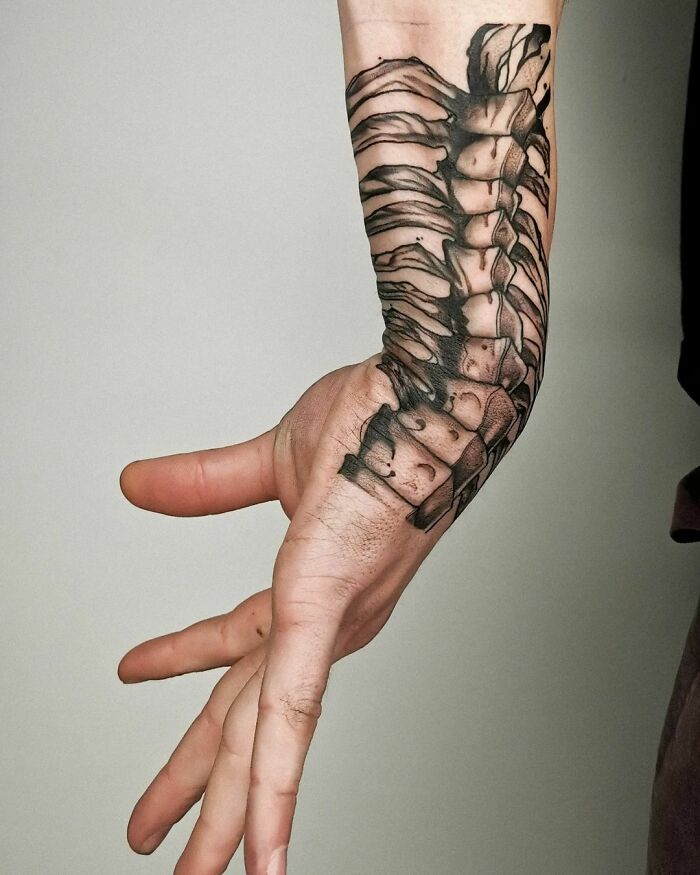 Wrist tattoo of a detailed spine design, showcasing a timeless accessory on the forearm.