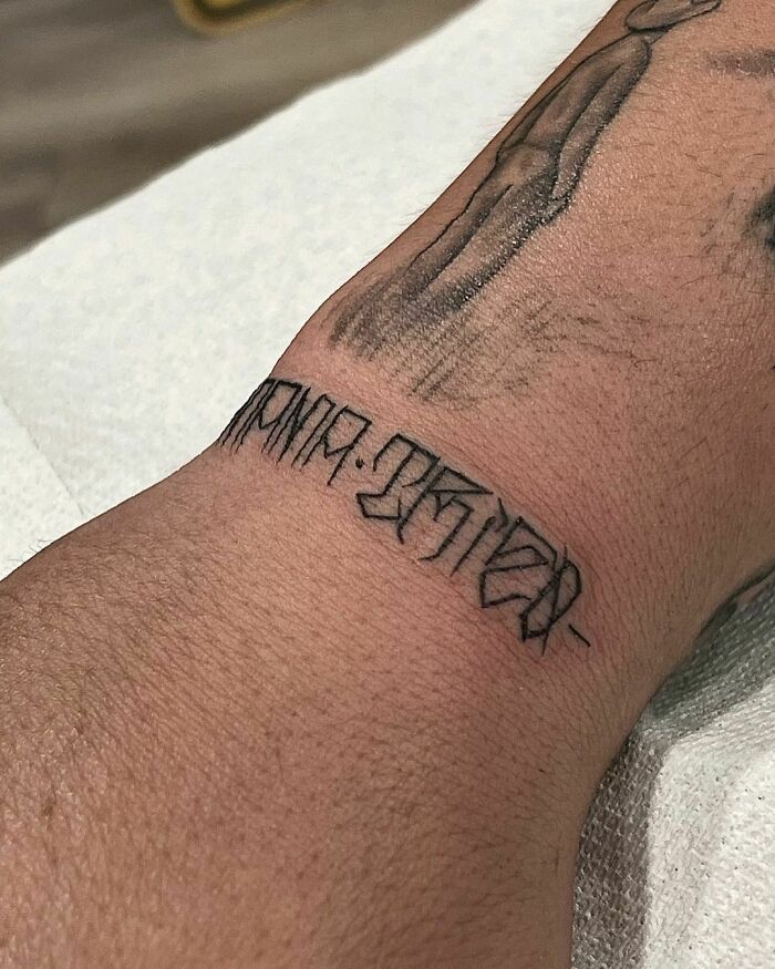 Geometric wrist tattoo in black ink, showcasing unique style and timeless accessory design.