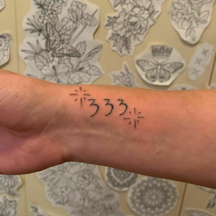 Wrist tattoo design featuring the number '333' with decorative sparkles.