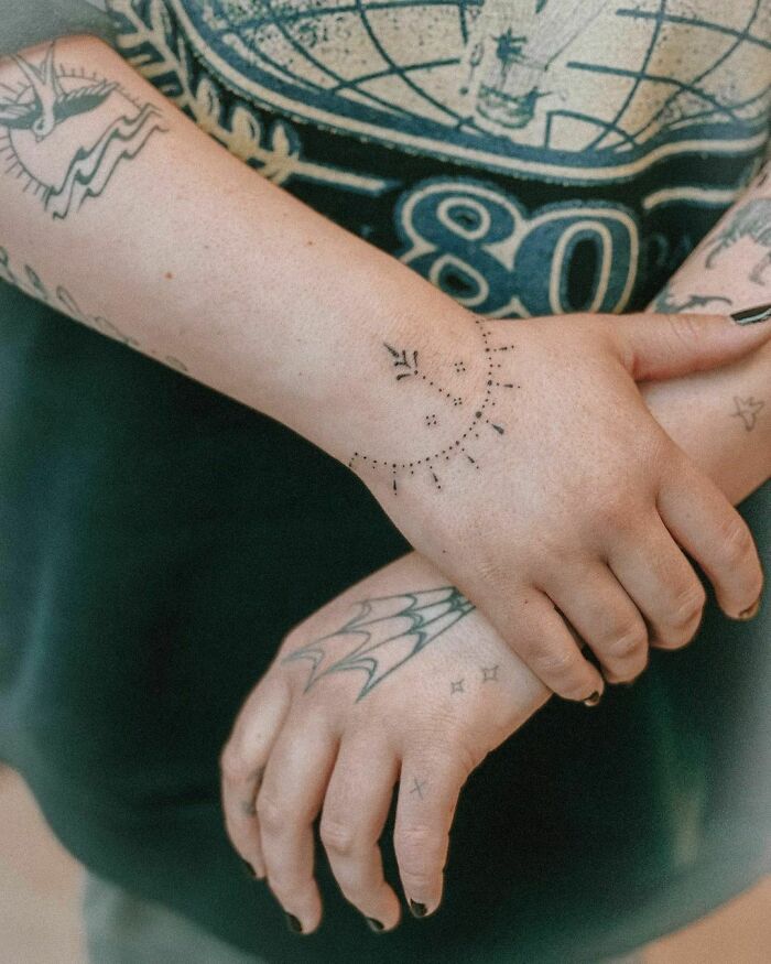 Close-up of unique wrist tattoos featuring celestial and geometric designs.