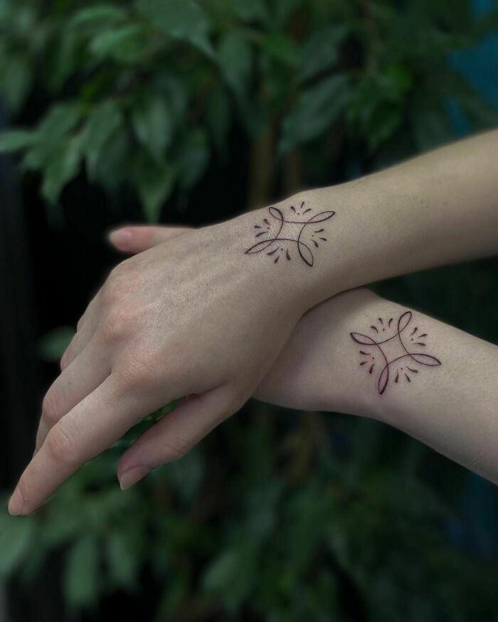 Simple wrist tattoos with abstract designs on two wrists.