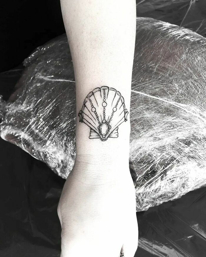 Ornate seashell wrist tattoo design showcasing elegant lines and intricate detailing.