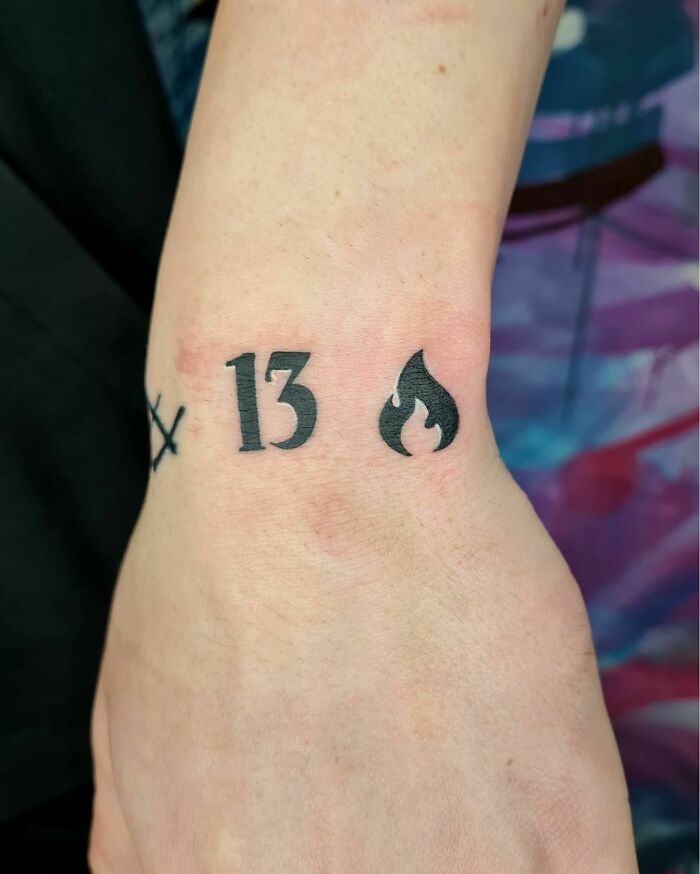 Wrist tattoo with number 13 and flame symbol, showcasing a stylish accessory idea.