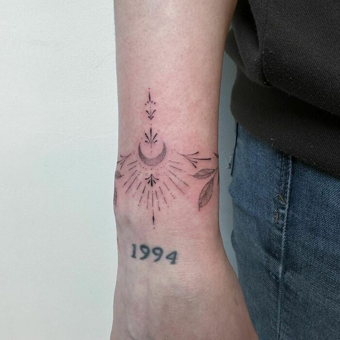 Wrist tattoo with celestial design and “1994” in bold font.