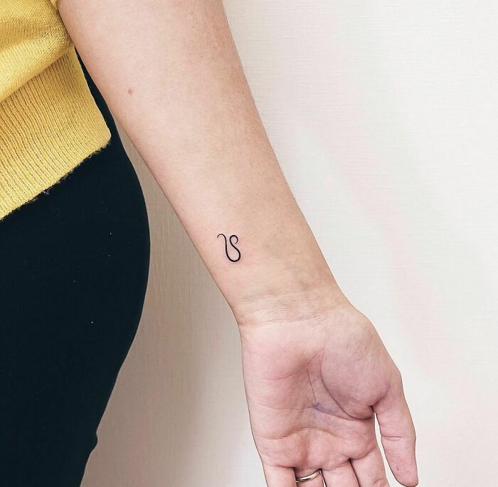 Minimalist wrist tattoo, elegant black line art on the inner forearm, highlighting stylish wrist tattoo ideas.