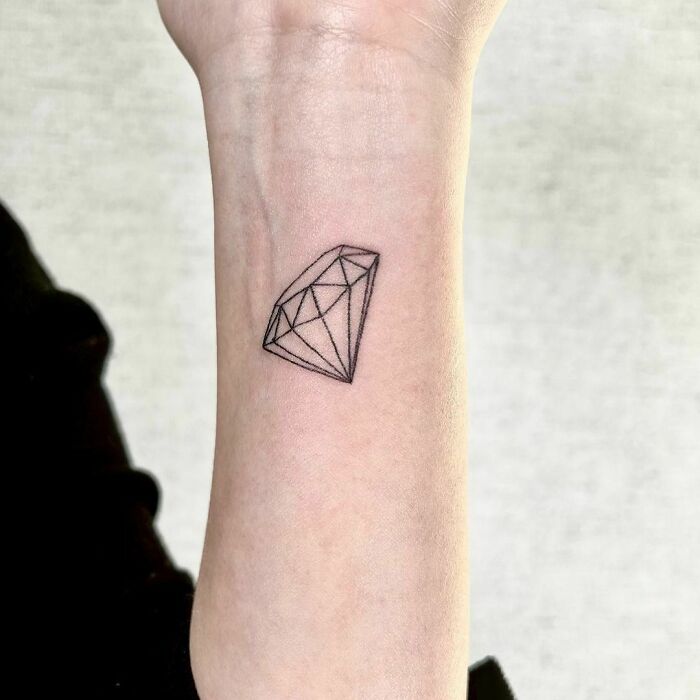 Minimalist wrist tattoo design featuring a geometric diamond shape.