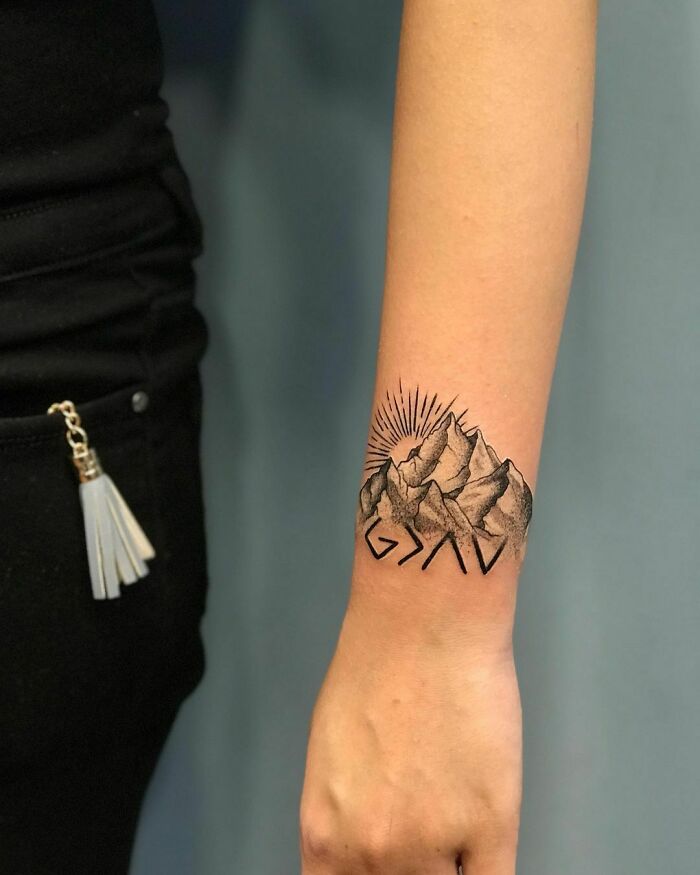 Mountain and sun wrist tattoo design, showcasing statement art.
