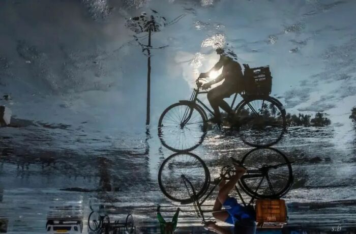 Reflection of a cyclist in a puddle, creating an amusing and artistic photo.