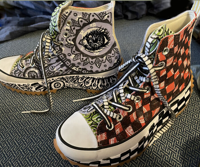 Unique shoes with artistic eye and checkerboard patterns displayed on carpet.