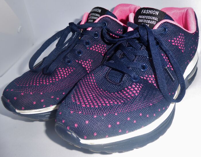 Navy and pink athletic shoes with a unique pattern showcased in a light box.