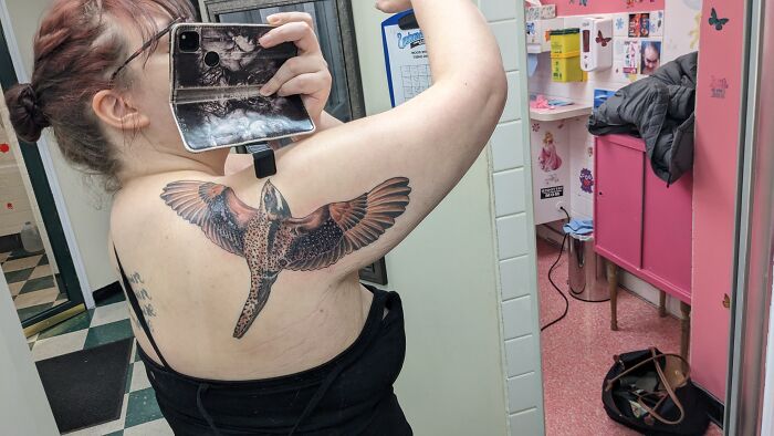 Person photographing cool tattoo of a bird on their back in a mirror.