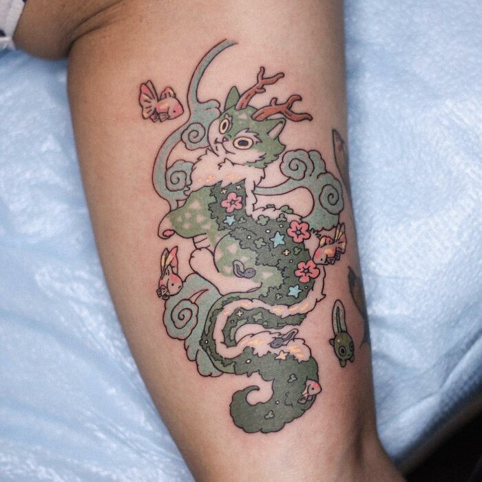 Tattoo featuring adorable animal-themed design of a whimsical cat with floral patterns and playful elements.