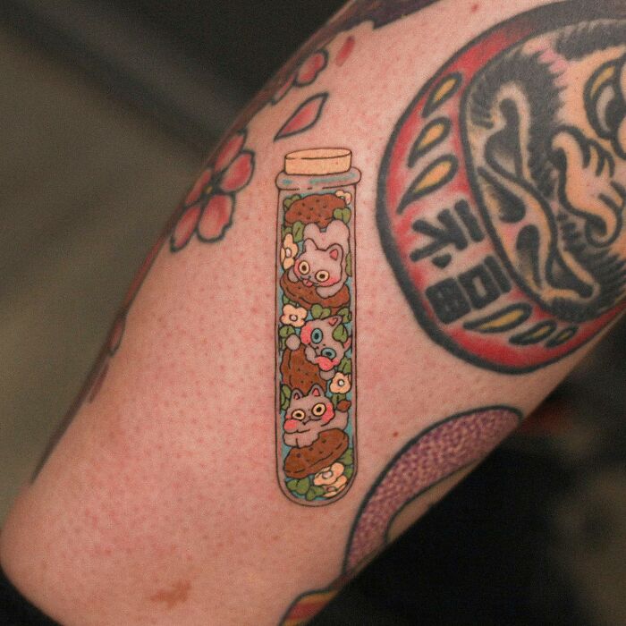 Tattoo of a vial filled with cute animals on an arm, showcasing adorable animal-themed designs.