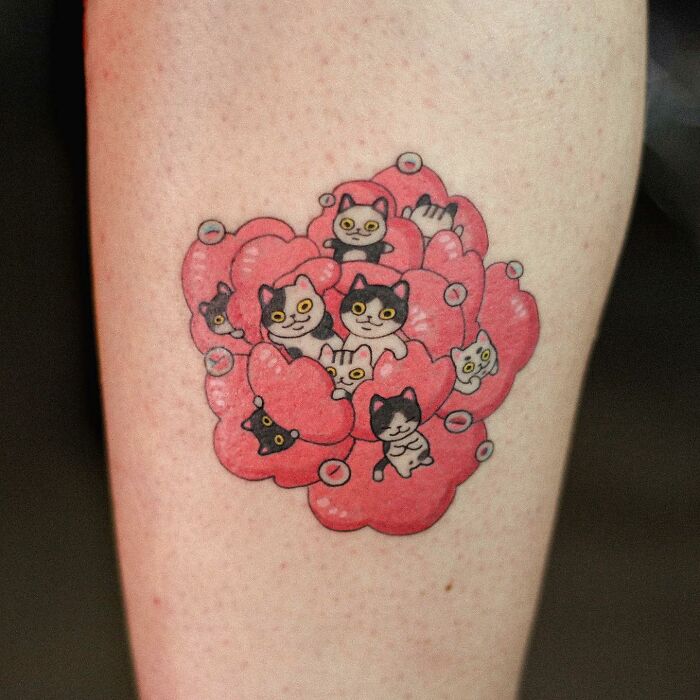 Adorable animal-themed tattoo of cartoon cats in pink hearts on skin.
