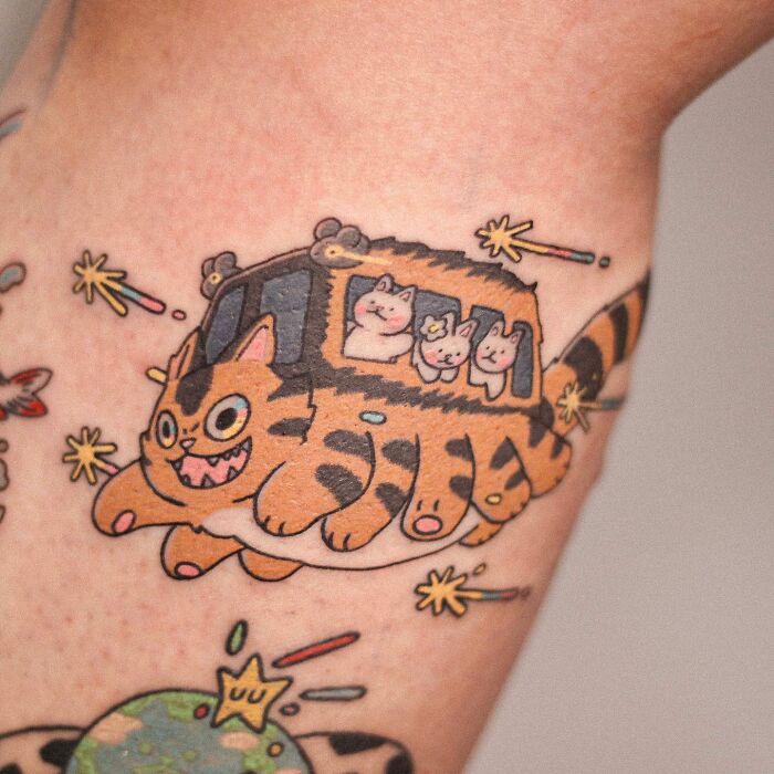 Adorable animal-themed tattoo of a playful cartoon cat bus with smiling passengers.