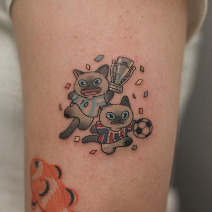 Adorable animal-themed tattoo featuring playful cats with a trophy and soccer ball.