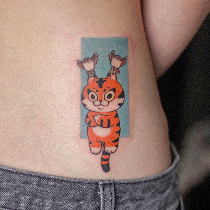 Animal-themed tattoo of a cute tiger with birds on its head, showcasing artistic design.
