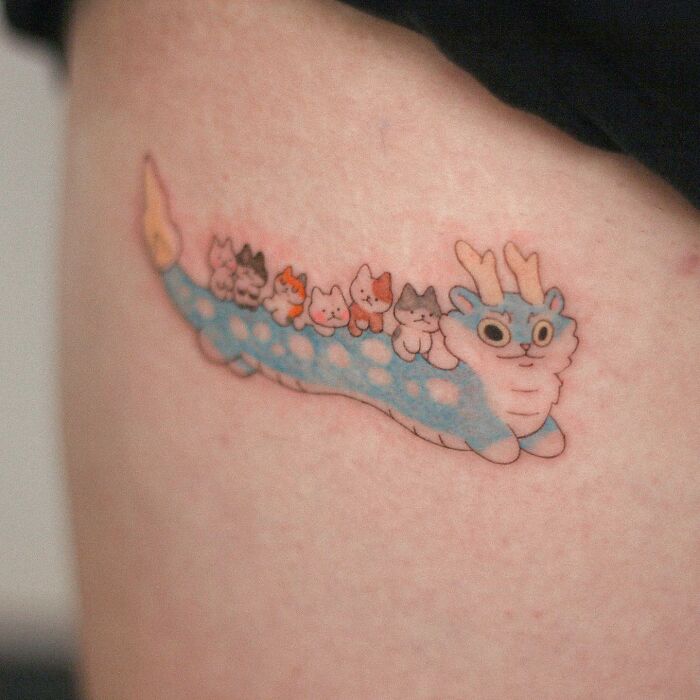 Adorable animal-themed tattoo of a whimsical creature with cats on its back, in blue and pink colors.