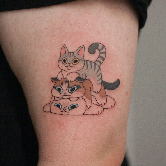 Adorable animal-themed tattoo of three stacked cartoon cats on an arm.