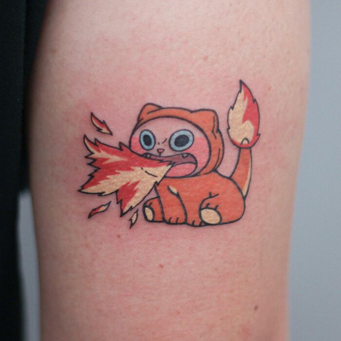 Adorable animal-themed cat tattoo breathing fire on skin.