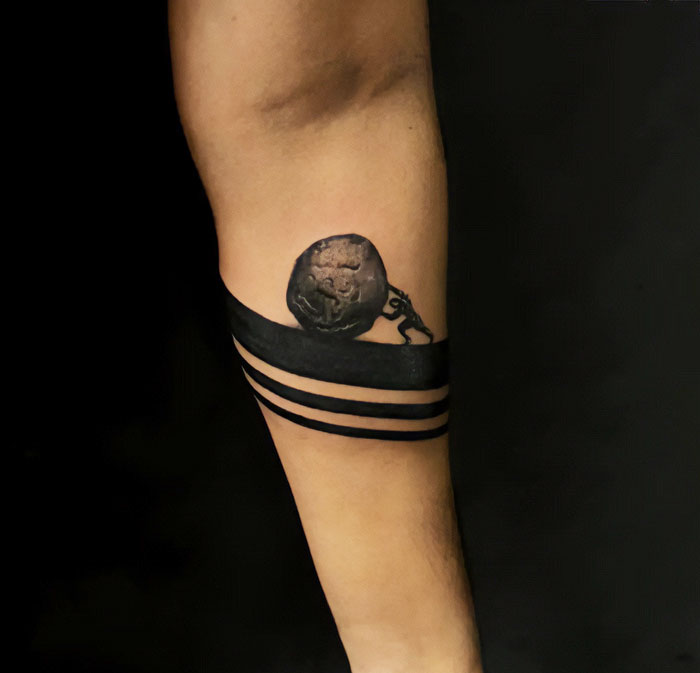 Black armband tattoo design with intricate chain and globe detail on forearm.