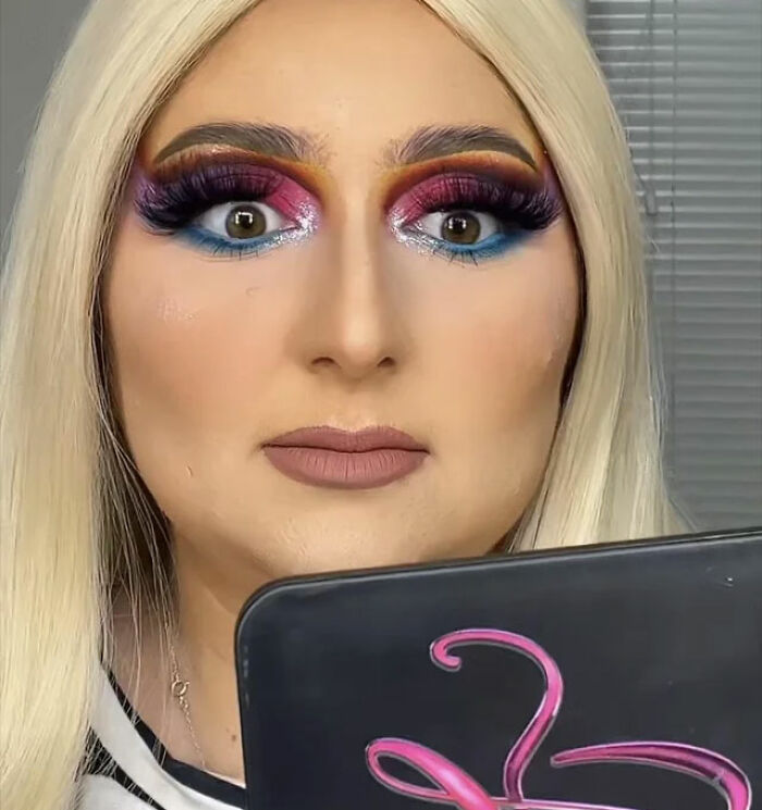 Makeup mishap with bright eyeshadow and dramatic lashes, person looking surprised, holding a palette.