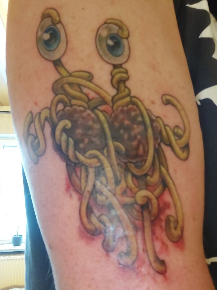 Creative tattoo of a spaghetti monster with eyes on an arm.