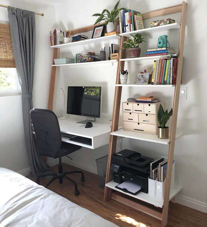 Creative home office decoration with a ladder shelf, books, plants, and a workspace featuring a computer and printer.