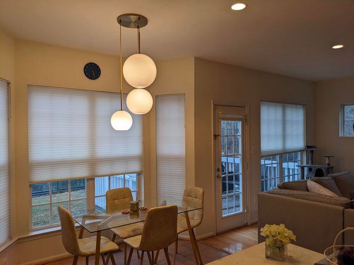 Modern dining area with chic pendant lights, glass table, and beige chairs—home decoration ideas for a stylish interior.