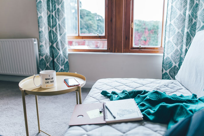 Cozy living room with creative decoration, including a mug, phone, and notebook on a table by a patterned curtain.