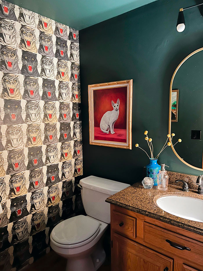 Bold wallpaper and cat painting in an eclectic bathroom decor.