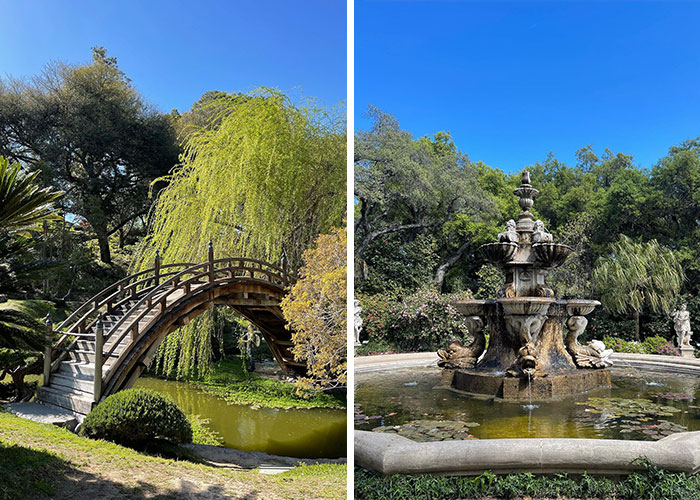 Wooden arched bridge over pond and ornate stone fountain in lush famous gardens under a clear blue sky.