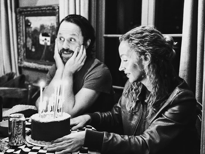 Man and woman celebrating with a birthday cake featuring lit candles, showcasing celebrity twins and great pairs.
