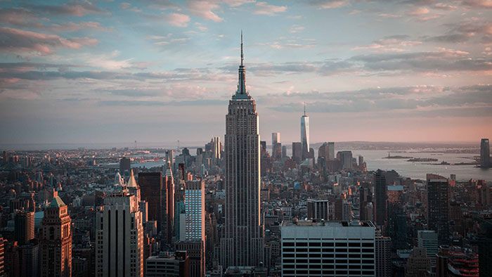 Empire State Building towering over New York City skyline at sunset, illustrating fun facts about physics in architecture.