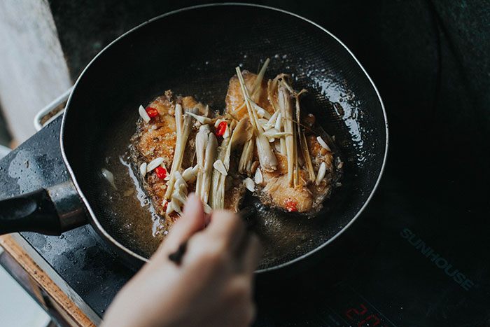 Person cooking in a pan with herbs and spices, showcasing a fun hobby to pursue.